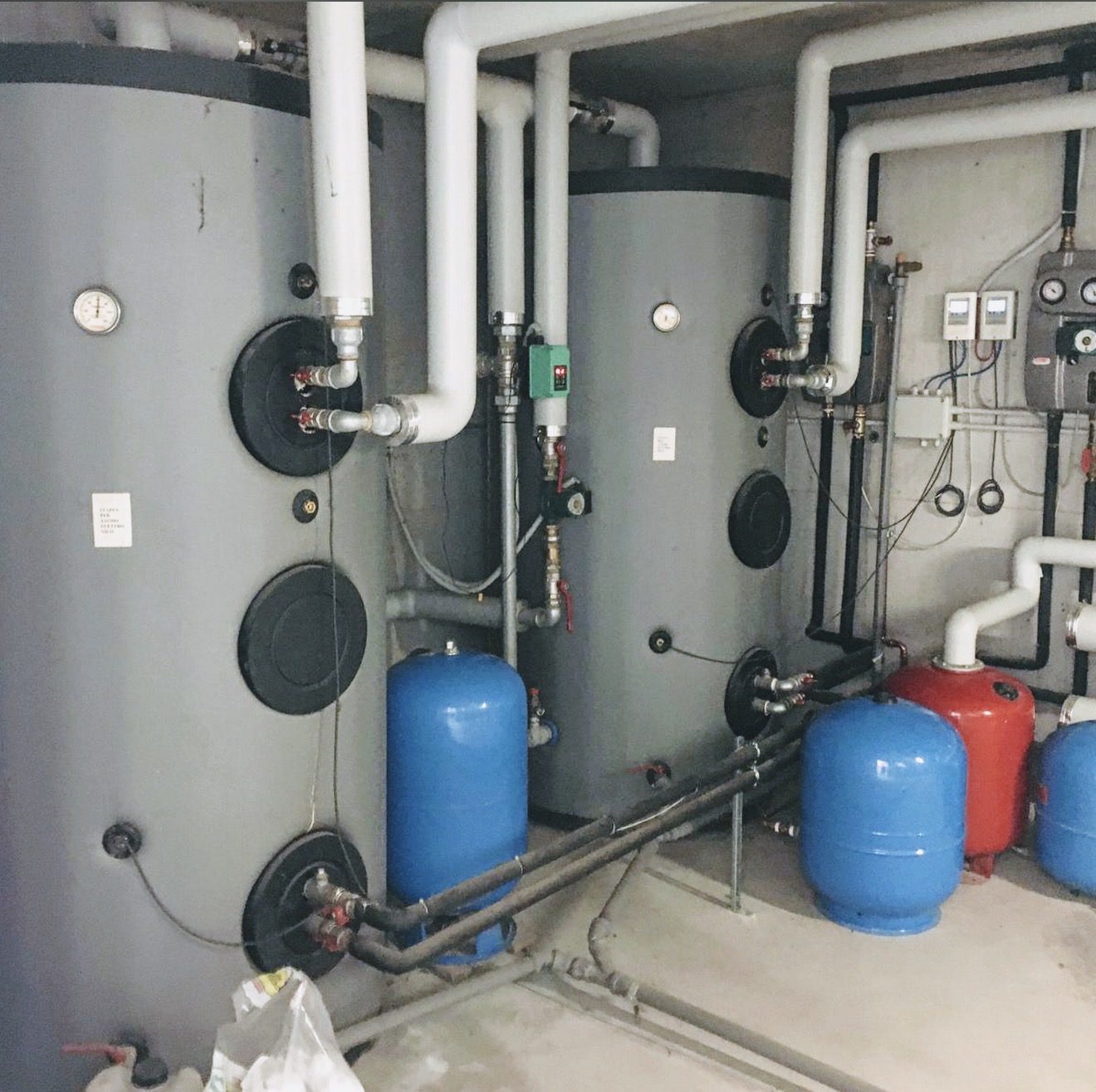 Accumuli per l'acqua calda sanitaria, vasi di espansione e gruppi di regolazione in una centrale termica condominiale.